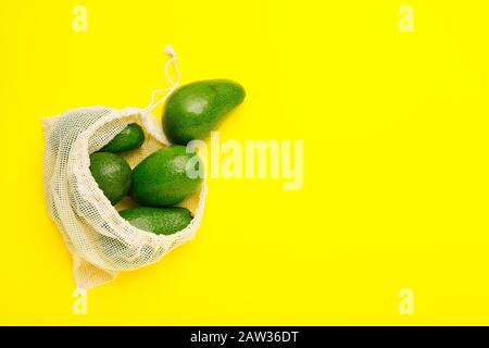 Avocados frutta in bianco sacchetto eco tessuto riutilizzabile. Sacchetto in tessuto riciclato per frutta o verdura. Plastica libera, concetto di shopping di zero sprechi. Minimo Foto Stock