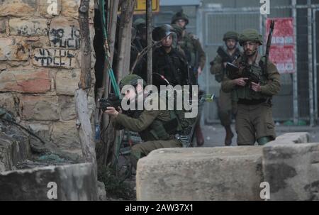 (200206) -- HEBRON, 6 febbraio 2020 (Xinhua) -- Un soldato israeliano punta la sua arma ai manifestanti palestinesi durante gli scontri nella città di Hebron, 6 febbraio 2020. (Foto Di Mamoun Wazwaz/Xinhua) Foto Stock