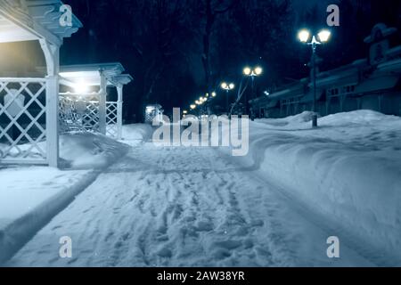 Vicolo del parco della città in una serata invernale con lanterne e gazebo Foto Stock