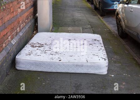 Vecchio materasso scaricato sul pavimento in una strada residenziale a Harborne, Birmingham, Regno Unito Foto Stock