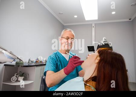 medicina, odontoiatria e concetto di assistenza sanitaria - sorridente dentista professionista maschio con lo specchio della bocca che controlla i denti del paziente giovane femmina a. Foto Stock