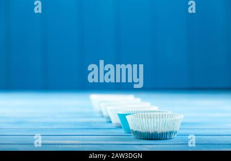 Porta cupcake in carta su sfondo rustico di legno blu. Foto Stock