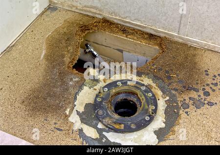 Un pavimento della stanza da bagno che si è rotted via da danni dell'acqua. Questo particolare danno è stato causato da una perdita nella valvola dell'alimentatore della toilette che aveva causato una perdita di Foto Stock