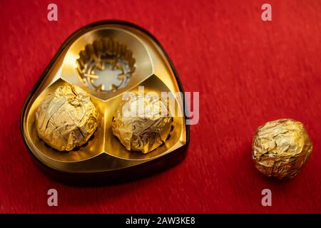Scatola di cioccolato di lusso contenente cioccolatini dorati avvolti in carta per San Valentino, anniversario, compleanno, carta regalo, poster, opuscolo, copertina della rivista Foto Stock