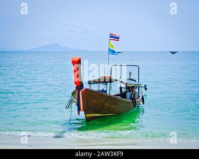 Tradizionale barca tailandese a coda lunga per i turisti ormeggiati vicino alla spiaggia sullo sfondo del mare azzurro. Isole in provincia di Krabi, Thailandia. Un ro Foto Stock