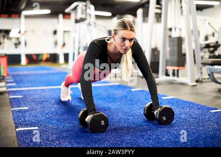 Una donna che fa spingere su il tappeto erboso in palestra. Foto Stock