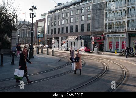 Dublino, Irlanda - 29th gennaio 2020: Pedoni che attraversano le piste del tram LUAS sul verde di St Stephens nel centro di Dublino Foto Stock