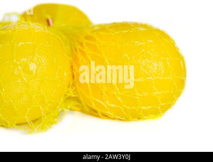 il negozio ha acquistato i limoni in un involucro di plastica gialla su uno sfondo bianco da vicino Foto Stock