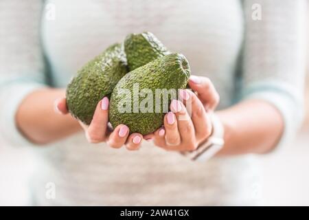 Le mani di una giovane donna tengono un fresco avocado. Foto Stock