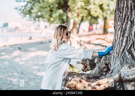 Ragazza raccogliere rifiuti dal parco. Raccoglie la lettiera in un sacchetto per la spazzatura Foto Stock