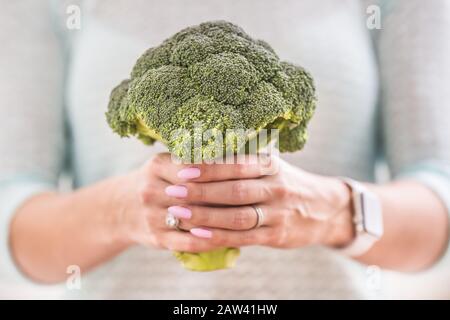 Le mani di una giovane donna tengono un broccoli fresco. Foto Stock