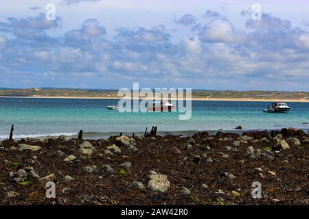 Una foto a 3 livelli di alghe sulle rocce, barche in un bel mare e un cielo nuvoloso. Preso In Cornovaglia, Inghilterra Foto Stock