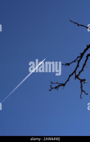 Un aeromobile a reazione lascia tracce di vapore, o contrails, che strisano attraverso il cielo. Foto Stock