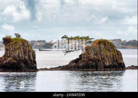 Le rocce intermaree nella baia di Siletz e le case fiancheggiano le coste lontane sotto cieli nuvolosi nella città di Lincoln sulla costa dell'Oregon. Foto Stock