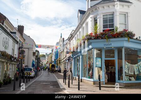 Il famoso negozio di moda Sea Salt sulla strada principale di Falmouth è decorato con fiori luminosi nel sole estivo con persone sulla strada acciottolata. Foto Stock