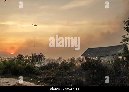 Un bombardamento d'acqua elicotteri cercare di spegnere incendi di terra nel villaggio di Rimbo Panjang, Kampar Regency, Riau, 6 ottobre 2019. Foto Stock