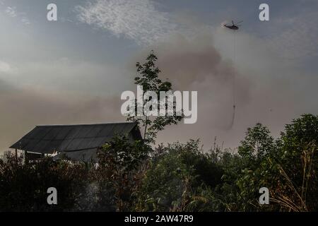 Un bombardamento d'acqua elicotteri cercare di spegnere incendi di terra nel villaggio di Rimbo Panjang, Kampar Regency, Riau, 6 ottobre 2019. Foto Stock