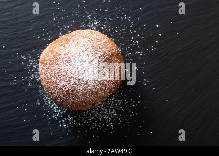 Food concept single Beignet francese lievito ciambella fritto pasta choux su sfondo lavagna in ardesia nera Foto Stock