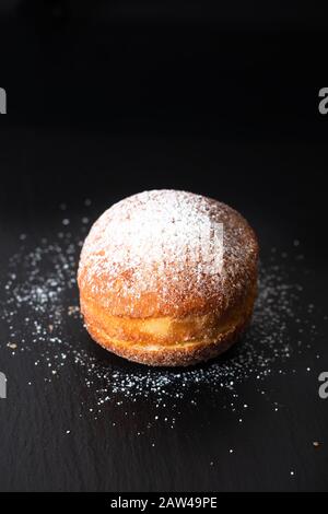 Food concept single Beignet francese lievito ciambella fritto pasta choux su sfondo lavagna in ardesia nera Foto Stock