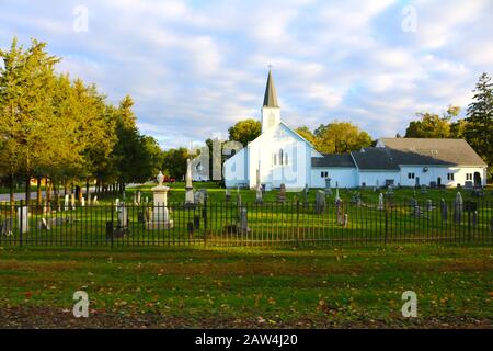 una piccola chiesa cittadina e cimitero in autunno Foto Stock