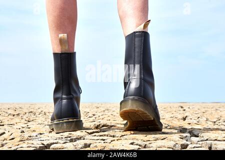 Franeker / Paesi Bassi - Giugno 02 2019: Gambe di una donna con Dr Martens 1460 Vegan Black scarpe su terreno fessurato. Foto Stock