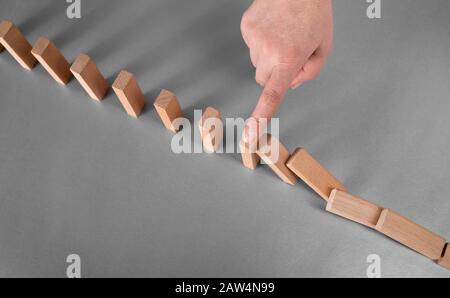 domino effetto prevenzione concetto. il dito smette di cadere domino Foto Stock