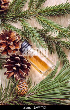 Bottiglia di olio aromatico di pino e abete con rami di pino e abete per la decorazione su sfondo di legno chiaro. Concetto di olio essenziale. Foto Stock