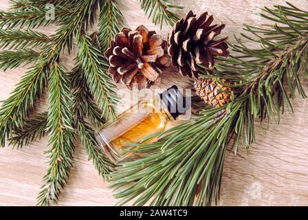Bottiglia di olio aromatico di pino e abete con rami di pino e abete per la decorazione su sfondo di legno chiaro. Concetto di olio essenziale. Foto Stock