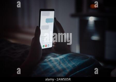 Internet addicted donna. Concetto di abuso telefonico. Donna sdraiarsi a letto con smartphone prima di dormire. Foto Stock