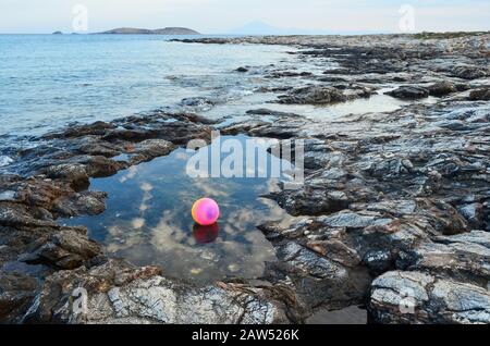 Palla multicolore in piscina in pietra naturale e riflessi del cielo al crepuscolo Foto Stock