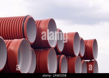 Composizione dei materiali da costruzione. Tubi fognari impilati su ripiani. Foto Stock