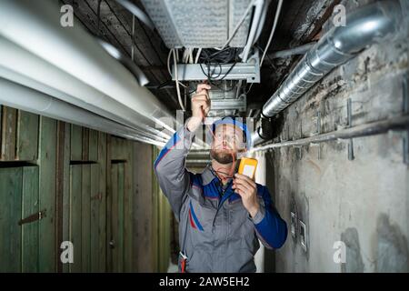 Lavoratore Maschile Che Indossa Hard Hat Con Un Multimetro Foto Stock