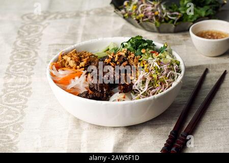 Ciotola di insalata tradizionale vietnamita noodle - Bun Bo Nam Bo, con manzo, noodle di riso, erbe fresche, verdure sottaceto e salsa di pesce Foto Stock