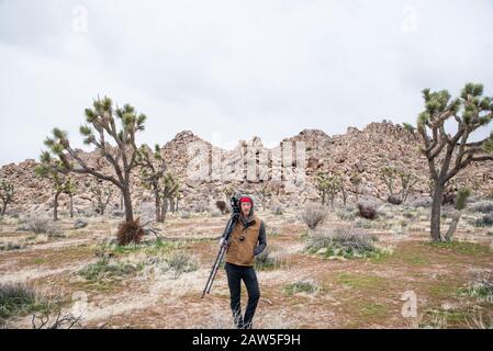 Uomo con grande macchina fotografica posto di fronte a mucchi di masso nel deserto Foto Stock