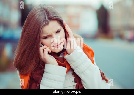 Non ti sento. Closeup ritratto bella donna ragazza parlare al telefono ascoltare attentamente cercando di sentire capire la conversazione isolato Foto Stock