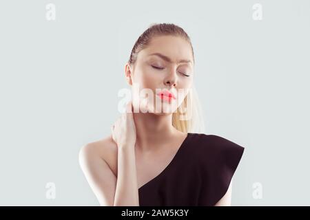 Malattia della schiena e della colonna vertebrale. Ritratto di closeup donna stanco massaggiante il suo collo doloroso isolato su sfondo bianco blu chiaro parete. Espressione del volto umano. Foto Stock