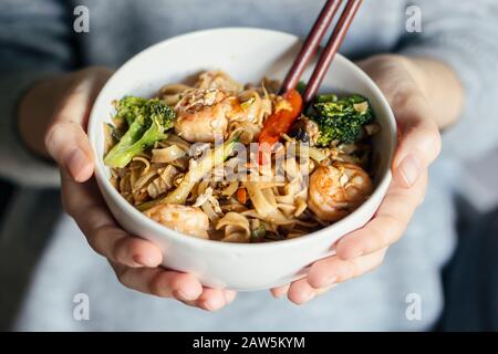 Chiudete le mani femminili tenendo una ciotola di noodle thai di pesce Foto Stock