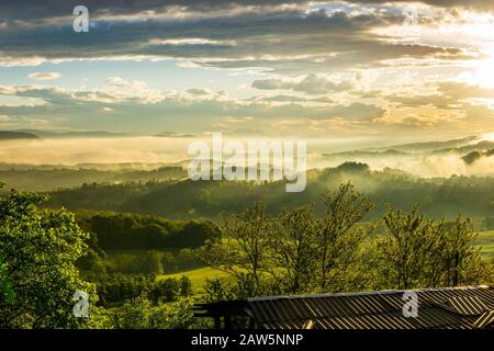 Paesaggio foggy con tramonto in montagna Foto Stock