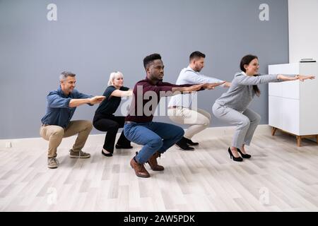 Sorridente multi etnico giovani imprenditori facendo sit ups insieme al lavoro Foto Stock