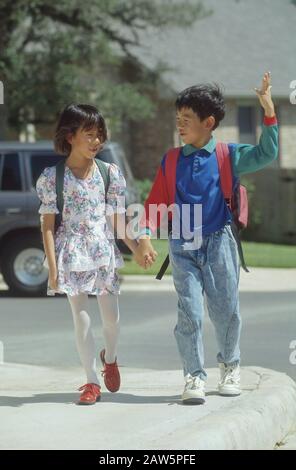 Fratello asiatico-americano e sorella che camminano a casa dalla scuola insieme ad Austin, Texas. Foto Stock