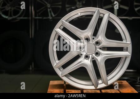 cerchi in lega argento, cerchi una nuova ruota su sfondo nero primo piano. CopySpace copia spazio, vista frontale su superfici in legno Foto Stock