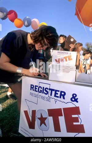 Giovane donna compila una carta di registrazione elettorale durante un rally politico all'aperto ad Austin, Texas. Foto Stock