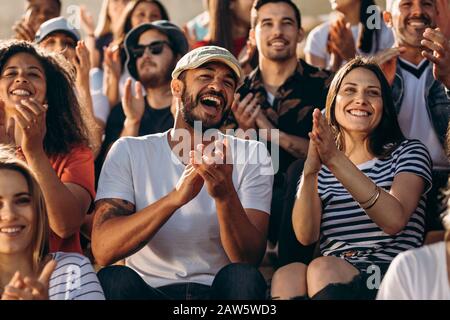 Gruppo di persone che guardano un evento sportivo e che si rallegrano. Folla entusiasta di appassionati di sport che applaudono seduto nello stadio. Foto Stock