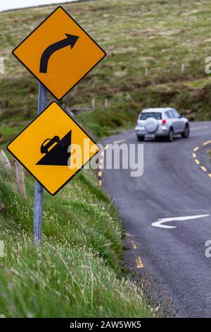 Avvertimento segnaletica stradale Pericolosa curva avanti e Ripida salita davanti al Skellig Ring vicino Portmagee, Iveragh penisola, County Kerry, Irlanda, Euro Foto Stock