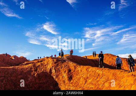 I turisti si arrampicano sul ripido terreno ondulato sulla cima di Uluru. Northern Territory, Australia Foto Stock