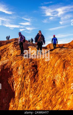 I turisti si arrampicano sul ripido terreno ondulato sulla cima di Uluru. Northern Territory, Australia Foto Stock