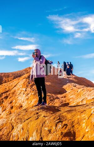 I turisti si arrampicano sul ripido terreno ondulato sulla cima di Uluru. Northern Territory, Australia Foto Stock