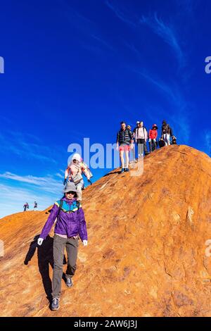 I turisti si arrampicano sul ripido terreno ondulato sulla cima di Uluru. Northern Territory, Australia Foto Stock