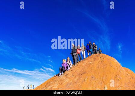 I turisti si arrampicano sul ripido terreno ondulato sulla cima di Uluru. Northern Territory, Australia Foto Stock