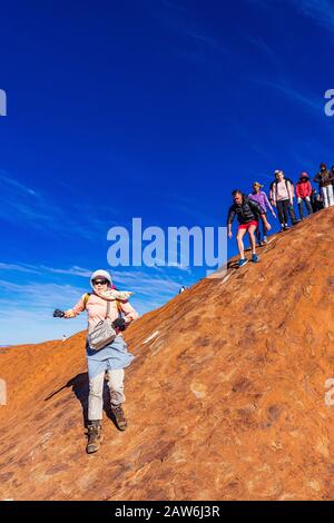 I turisti si arrampicano sul ripido terreno ondulato sulla cima di Uluru. Northern Territory, Australia Foto Stock